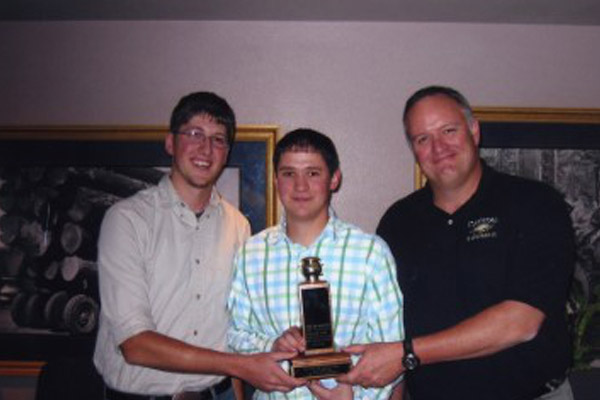 three men with a small trophy